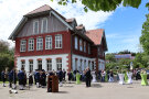 Blick auf das historische Gebäude, Haus Sigma. Im Vordergrund spielt die Blaskapelle und zahlreiche Gäste folgen den Klängen der Blasmusik. 