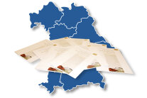 Karte mit den sieben Regierungsbezirken Bayerns und einigen Broschüren im Vordergrund