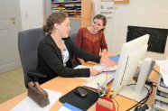 Zwei junge Frauen besprechen etwas in einem Büro