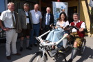 Gruppe steht um zwei Personen auf dem E-Tandem