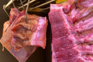 Geschlachtetes und zerlegtes Fleisch, das an einem Fleischerhaken hängt.