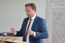 Ein Mann im blauen Anzug steht an einem Rednerpult.