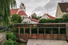 Die Streichwehranlage in Wittislingen, im Hintergrund die Pfarrkirche und Häuser.