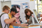 Eine Mitarbeiterin und Schüler an einem digitalen Puzzle.