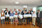 12 Bürgermeister und eine Bürgermeisterin im Dirndl halten die Förderplakate im Beisein von Amtsleiter Kreye und Europaabgeordneten Markus Ferber.