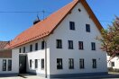 Ein weißes Gebäude mit vielen Fenstern und einem Dach aus Ziegeln.