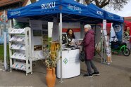 Ein Messestand mit zwei Frauen, einer Theke und einem Broschürenständer.