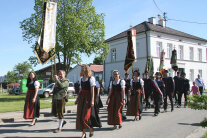 Ein Festzug mit Fahnen zieht zur Einweihung des Dorfgemeinschaftshauses durch Reichau.