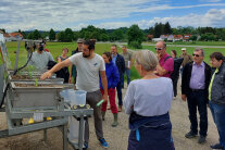 Landwirte und Anwohner aus Margertshausen betrachten einen aufgebauten Regensimulator.