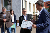 Übergabe eines kleinen Schildes durch den Amtsleiter an den Bürgermeister.