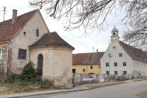 Die sanierungsbedürftige Kapelle mit Schloss, verbunden durch einen Bauzaun.