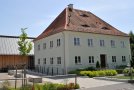 Sanierter Pfarrhof mit Walmdach, Fassade grau, alle Fenster und Hauskanten weiß hervorgehoben