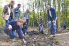 Eine Gruppe von stehenden und knieenden Männern und Frauen untersuchen den Waldboden.