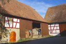 Landwirtschaftliche Scheune mit großem Schiebetor, rotem Fachwerk und neuem Holztor