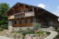 Das niederbayerisches Waldlerhaus mit Balkon wurde renoviert und steht auf einem mit Steinen befestigten Hügel.