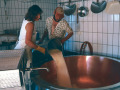 Käserei der Alpe Oberberg. Frau und Mann schütten Rohmilch in den Kupferkessel.